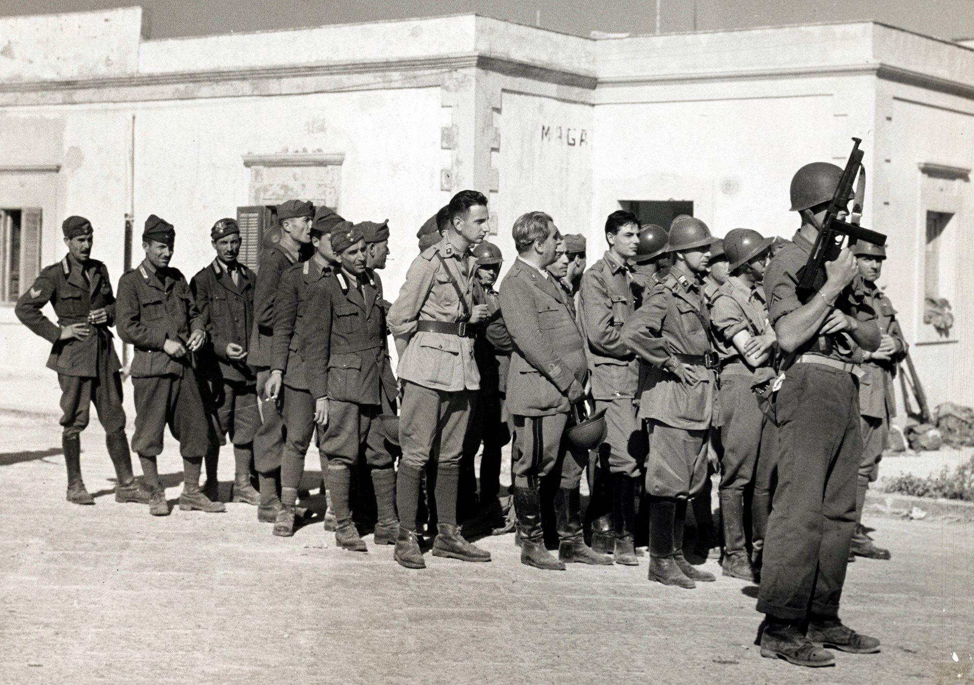 Glad to be out of the war, this mixed bag of Italian POWs is guarded by a US Coastguardsman armed with M1A1 Thompson SMG. NARA