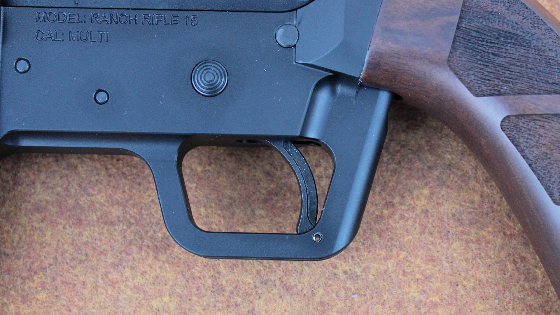 FM Products Rancher Rifle left-side, close-up view of trigger aluminum housing receiver satmping safety button wood grip on right side