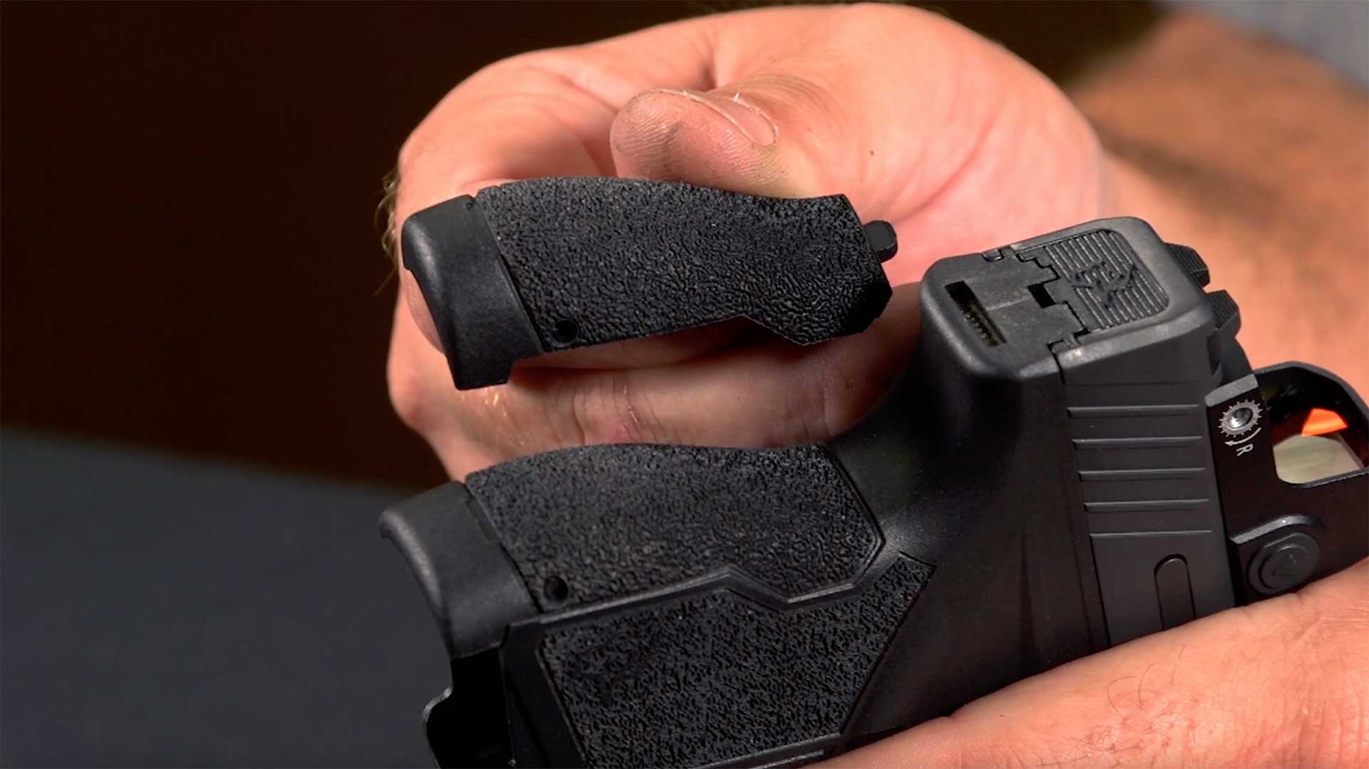Man showing interchangeable backstraps on the Taurus GX4 T.O.R.O. pistol.