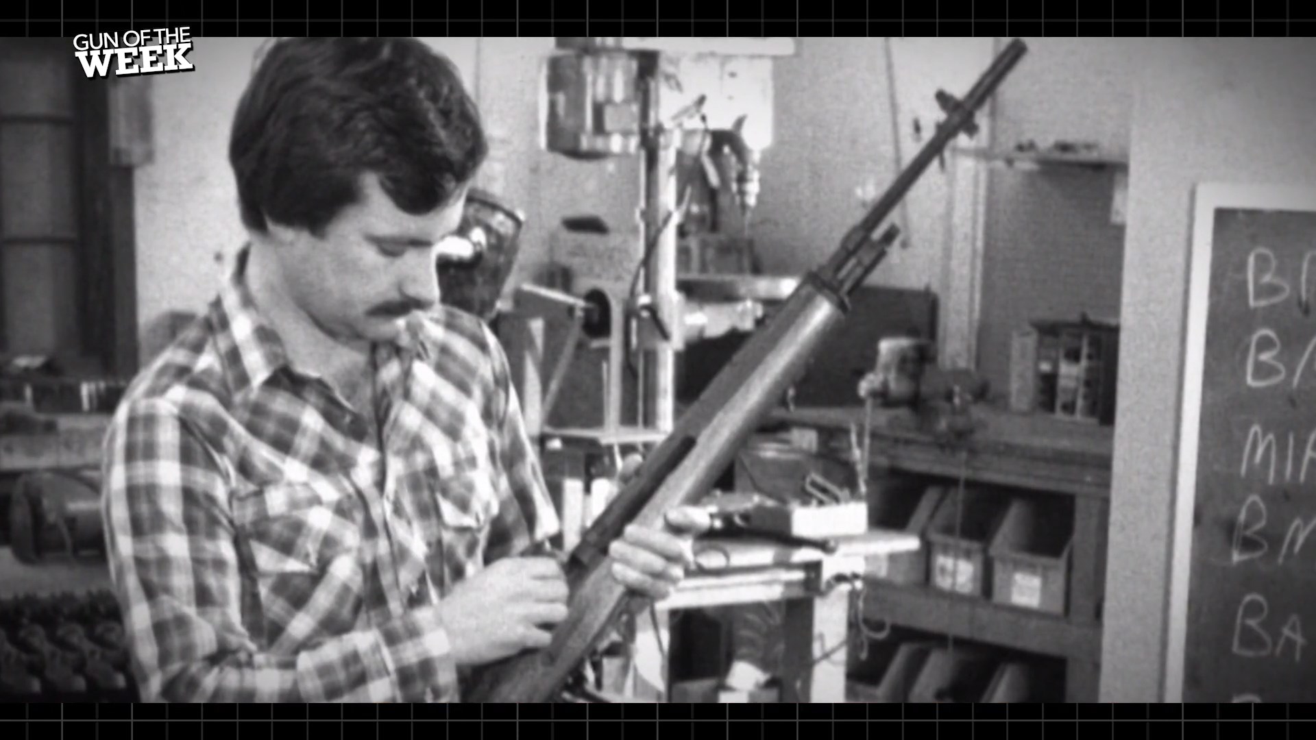 vintage black white image of man holding M1A rifle gunsmith shop indoors GUN OF THE WEEK text top left corner