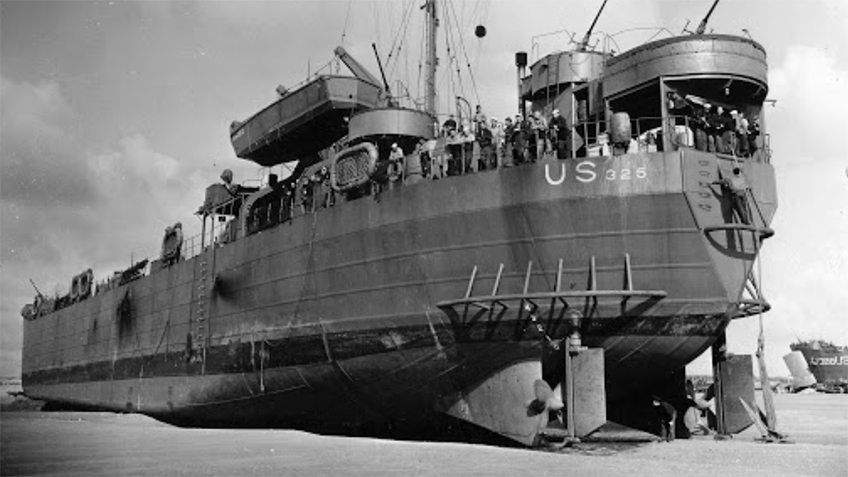 The stern section of LST 325 while beached at Normandy. Note the two propellers and the smaller LCVP Higgins boat hanging on the davits.