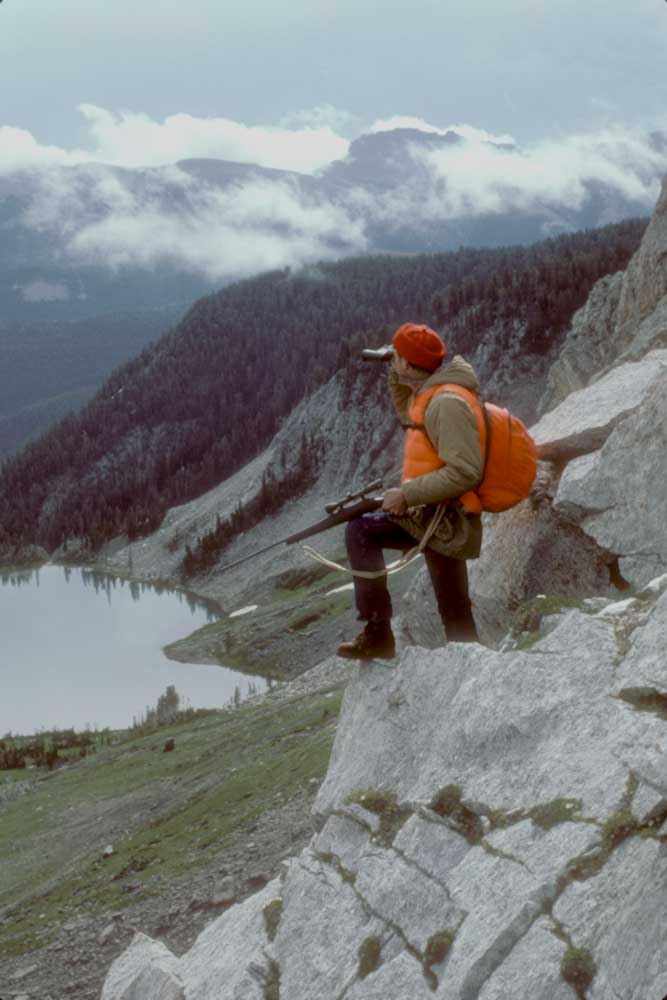 mountain hiking lake hills trees rocks water man orange safety hunting hunter vantage