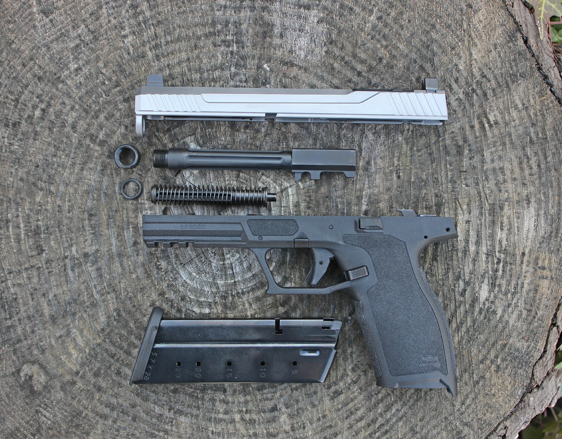 Palmetto State Armory 5.7 Rock Rk1 pistol disassembled parts shown on log