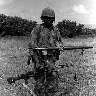 A soldier of the Eastern Caribbean Defense Force poses with a captured RPG-2 rocket launcher and a Bren L4 light machine gun (7.62 NATO).