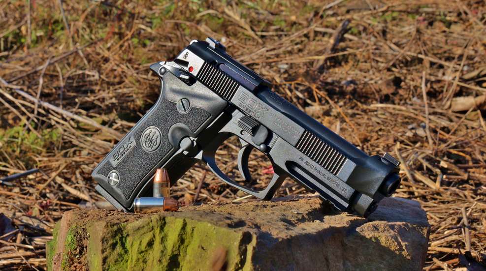 Beretta 80X Cheetah handgun shown outdoors on rock with ammunition dirt background sunrise sunset yellow glow lighting