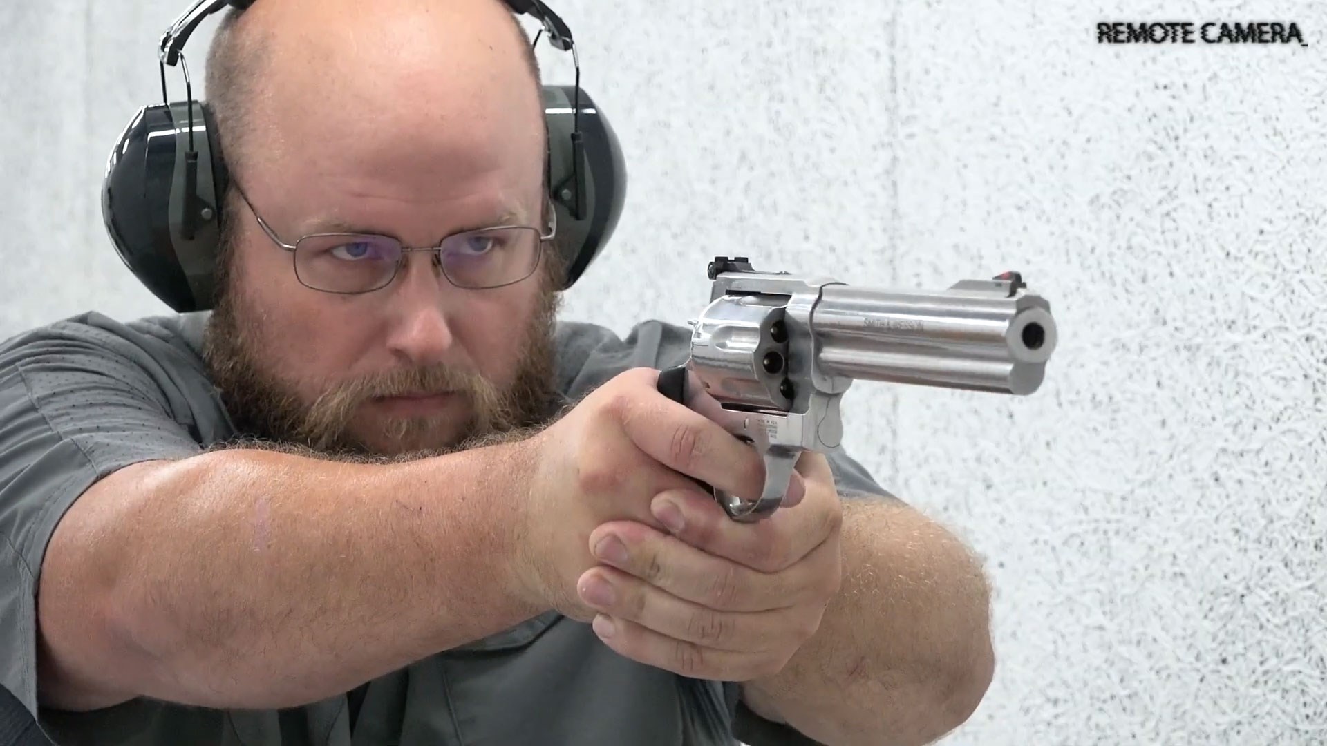 Man wearing glasses and ear muffs hearing protection shooting silver stainless steel Smith & Wesson Model 350 X-Frame revolver