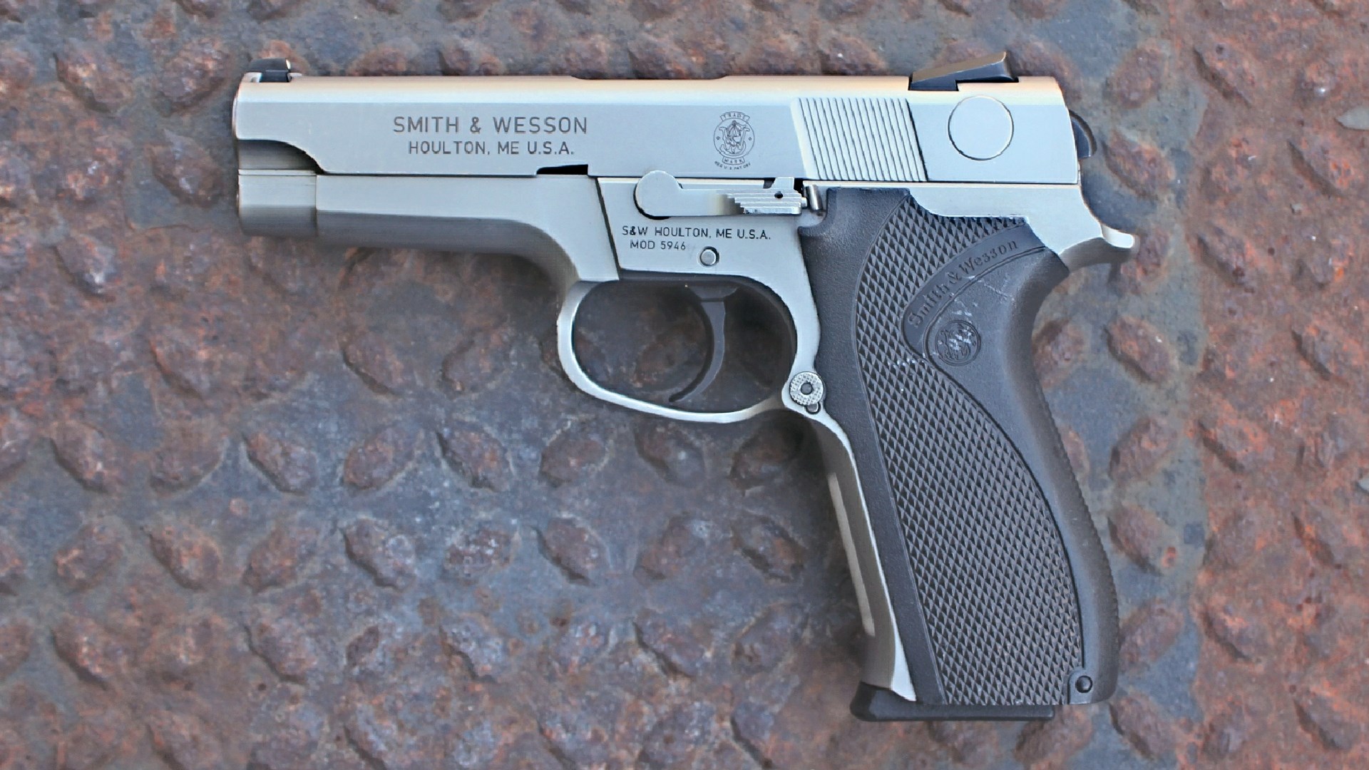 Smith & Wesson 5946 stainless steel pistol left-side view on rusted treadplate