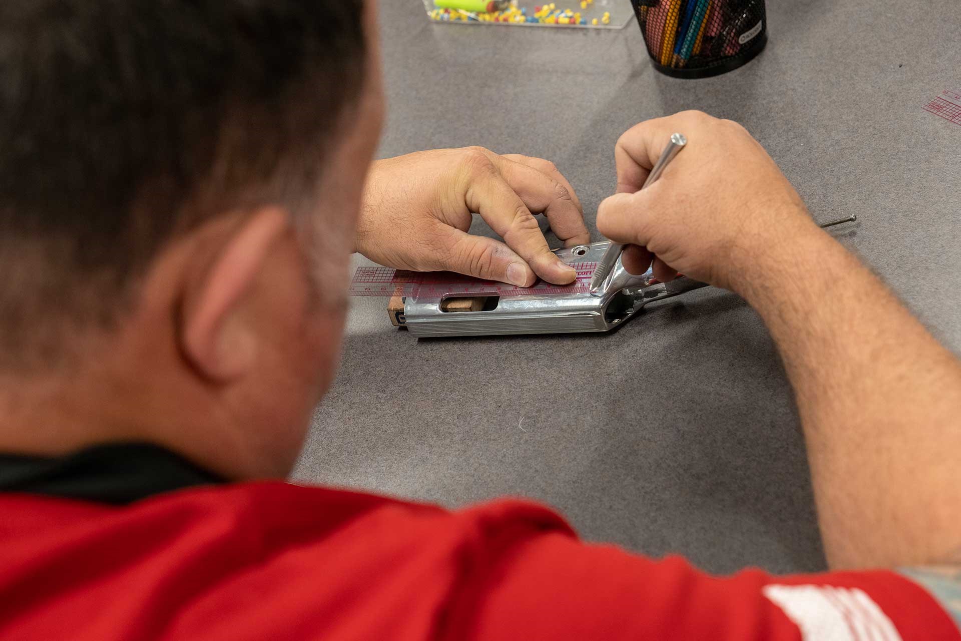 A man works to engrave a rifle receiver.