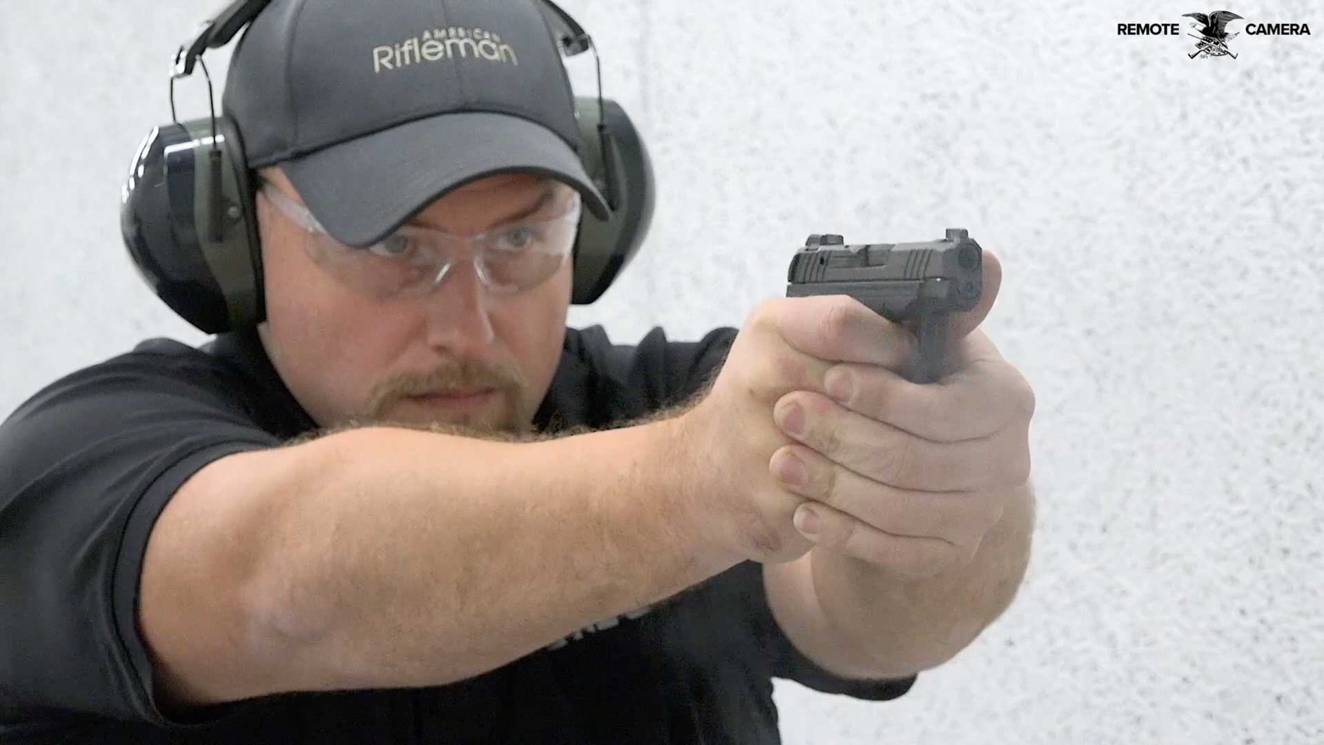 man black shirt ballcap earmuffs shooting black handgun pistol range guns
