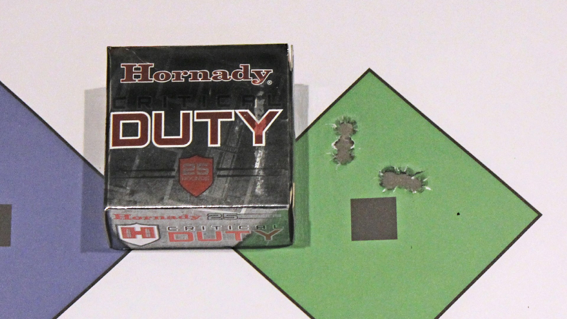 Hornady Critical Duty silver box ammunition shown next to diamond green target bullet holes accuracy 9 mm