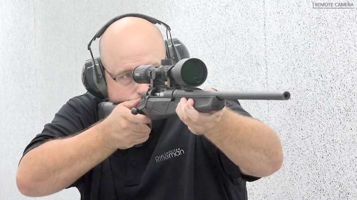 Bald man black shirt rifle shooting