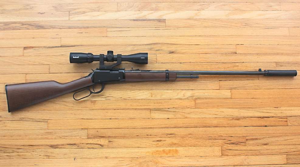 Henry Repeating Arms H001 Long Barrel 24" lever-action rifle shown on wood floor with Bushnell riflescope Silencer Central Banish 22 sound suppressor