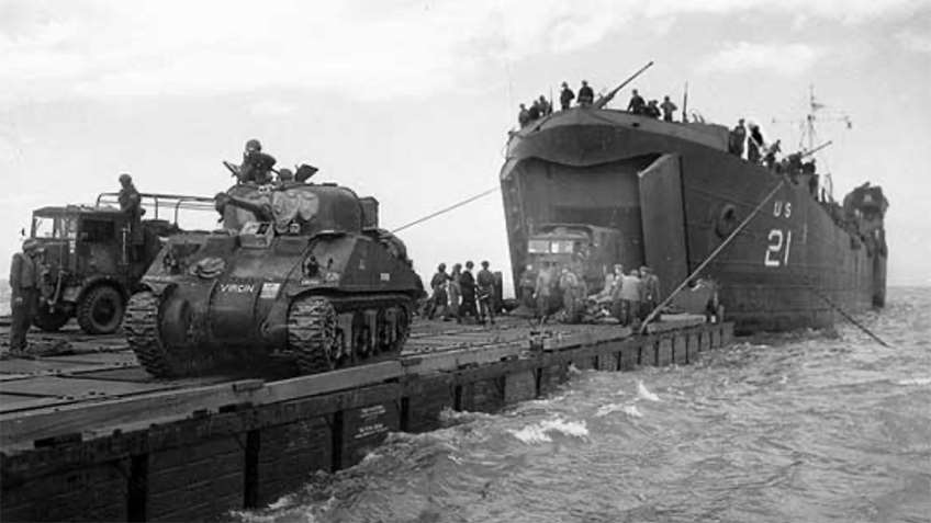 A Landing Ship, Tank unloading tanks and other vehicles from its bow ramp.