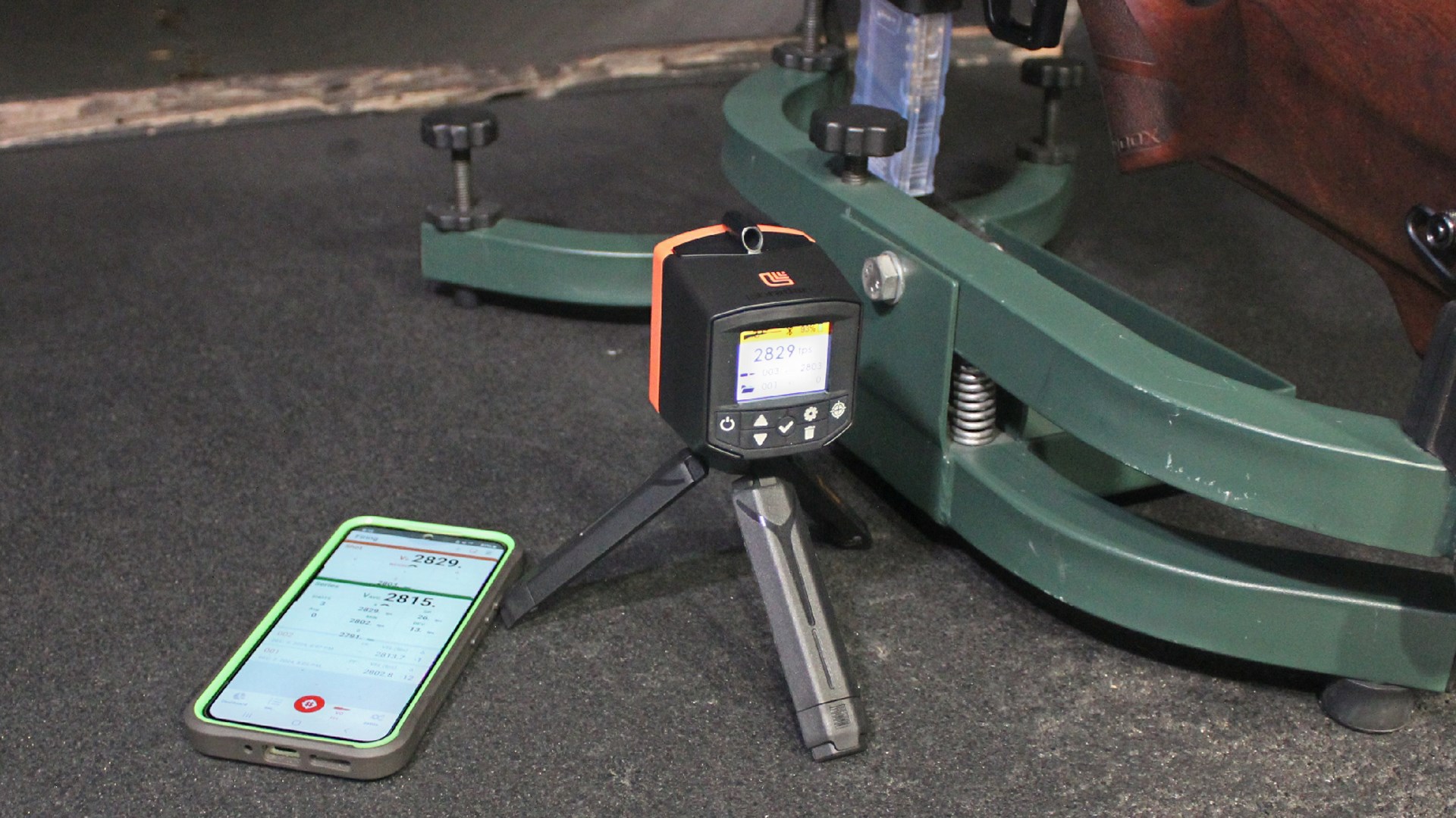 LabRadar chronograph shown next to cellular phone with screen on and rifle rest
