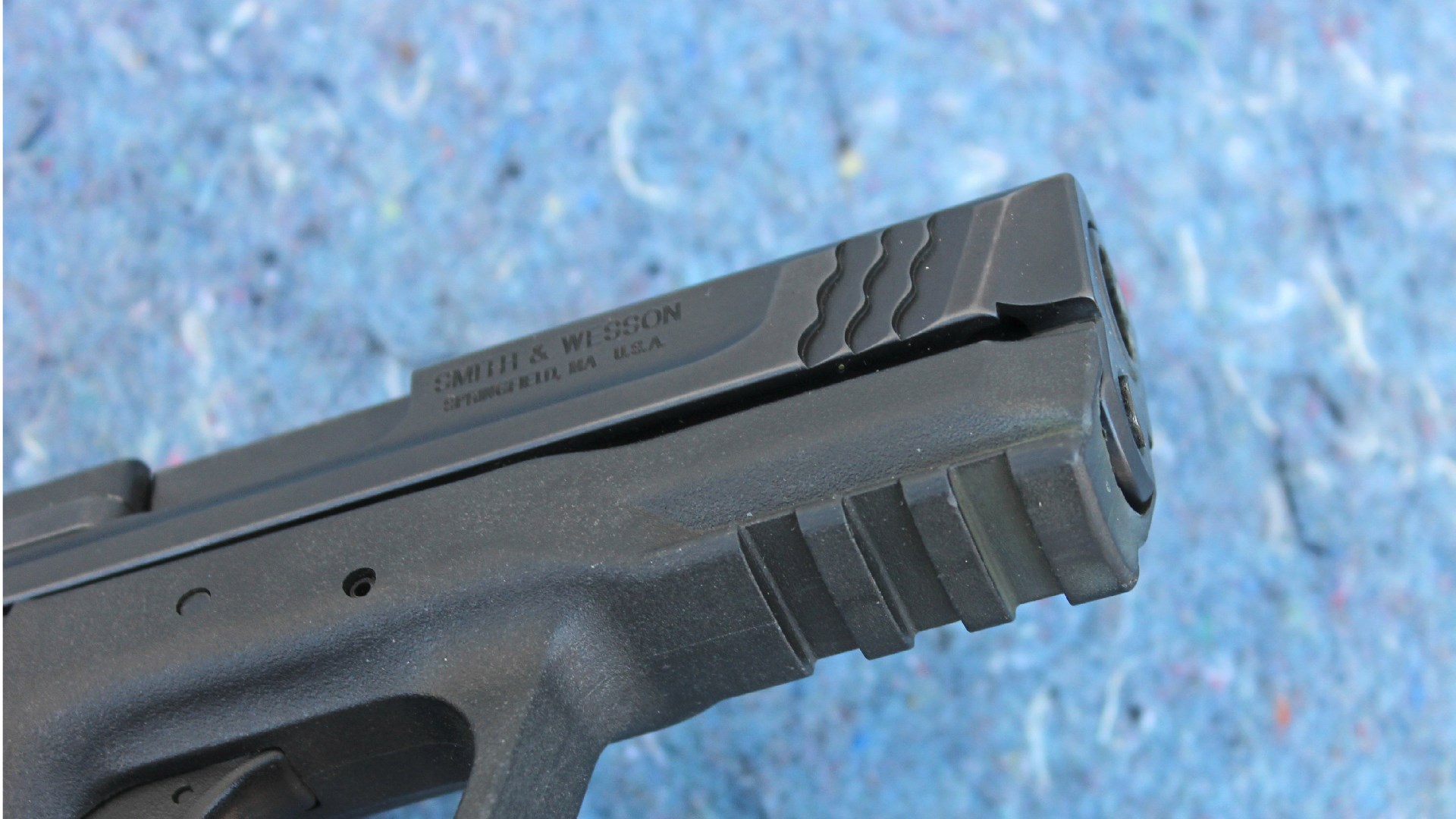 Smith & Wesson M&P 45 accessory rail closeup view underside of black polymer handgun frame shown on blue background