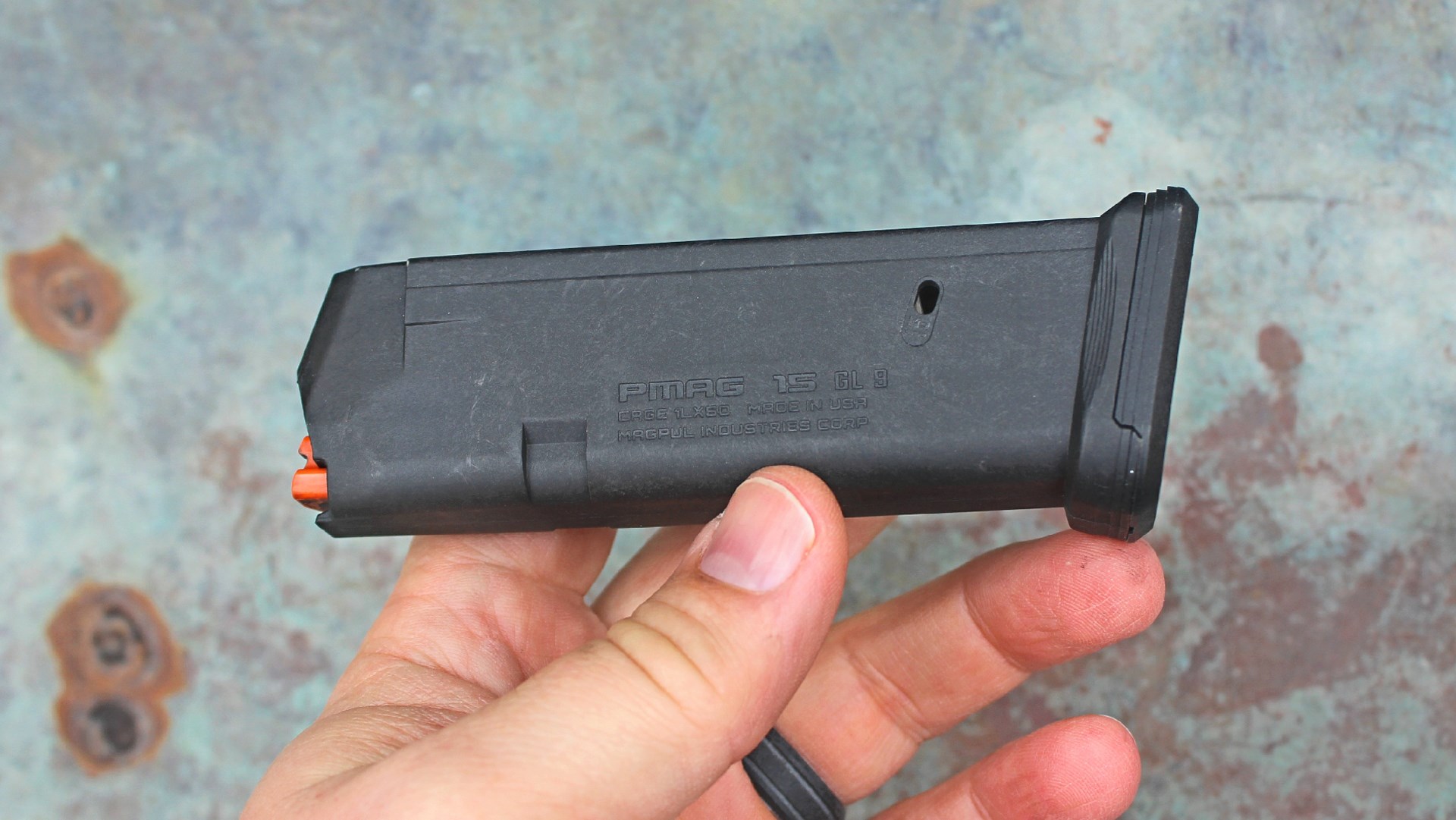 black polymer magpul p-mag shown in hand with rusty steel background