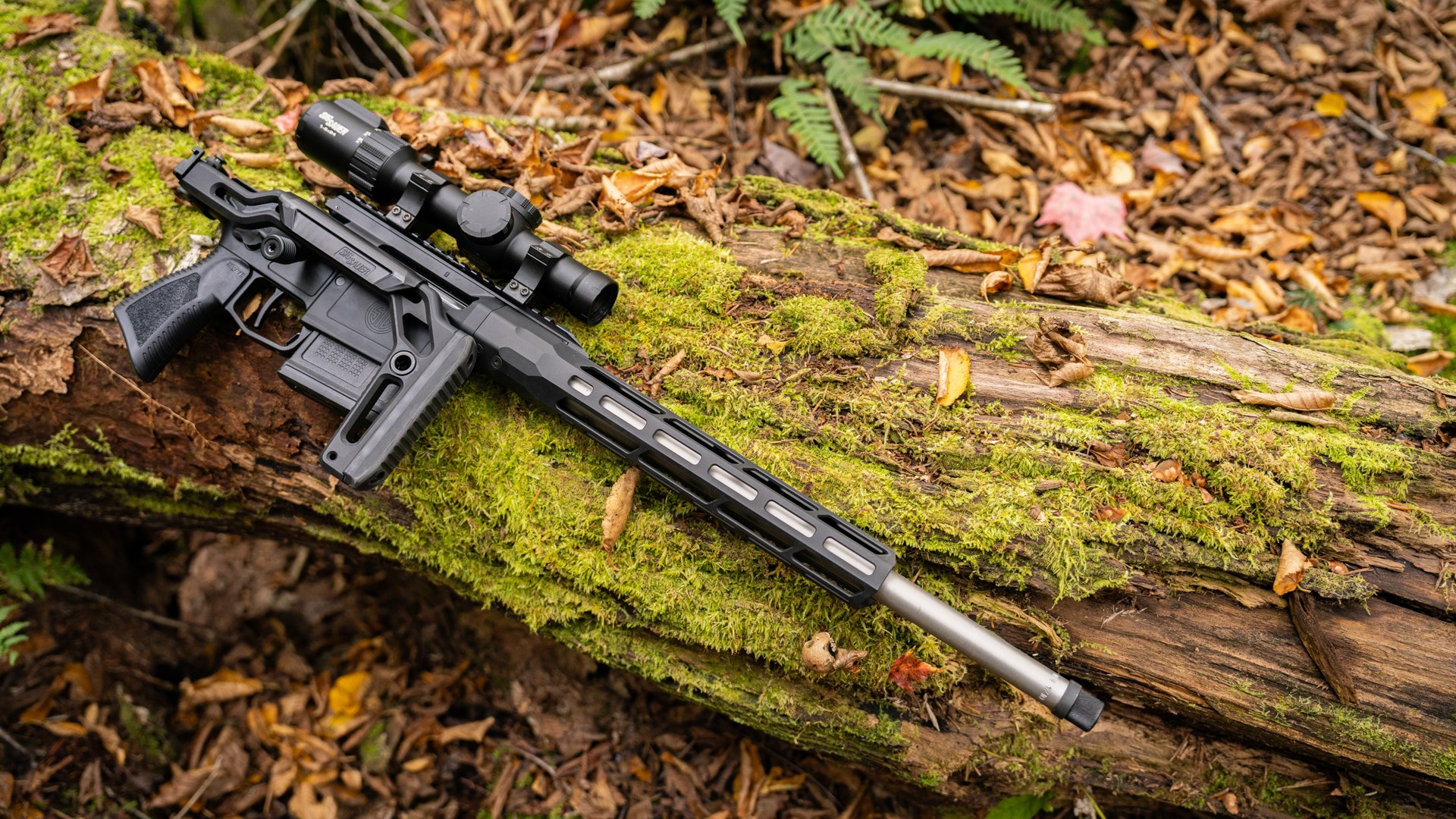 Right side of the SIG Sauer Cross Trax, sitting on a mossy log with its stock folded.