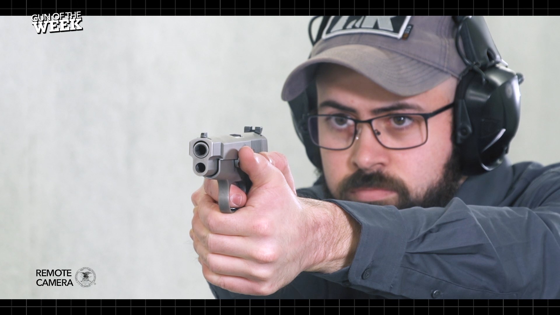 bearded man wearing cap glasses ear muffs shooting silver gray stainless steel FN America High Power 9 mm Luger pistol handgun indoors range