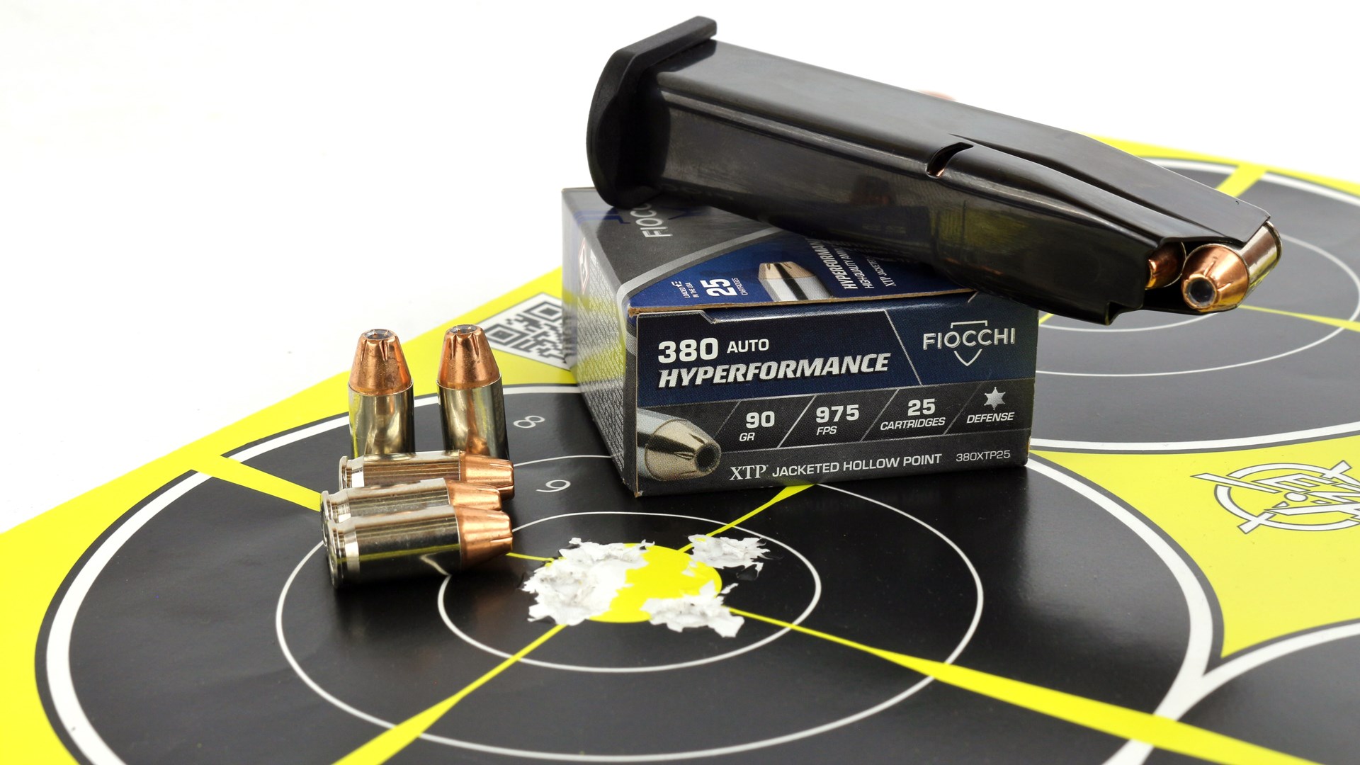 Fiocchi 380 Auto Hyperformance ammunition box shown on bullseye target with loose rounds ammunition cartridges loaded mag resting on top of ammunition box