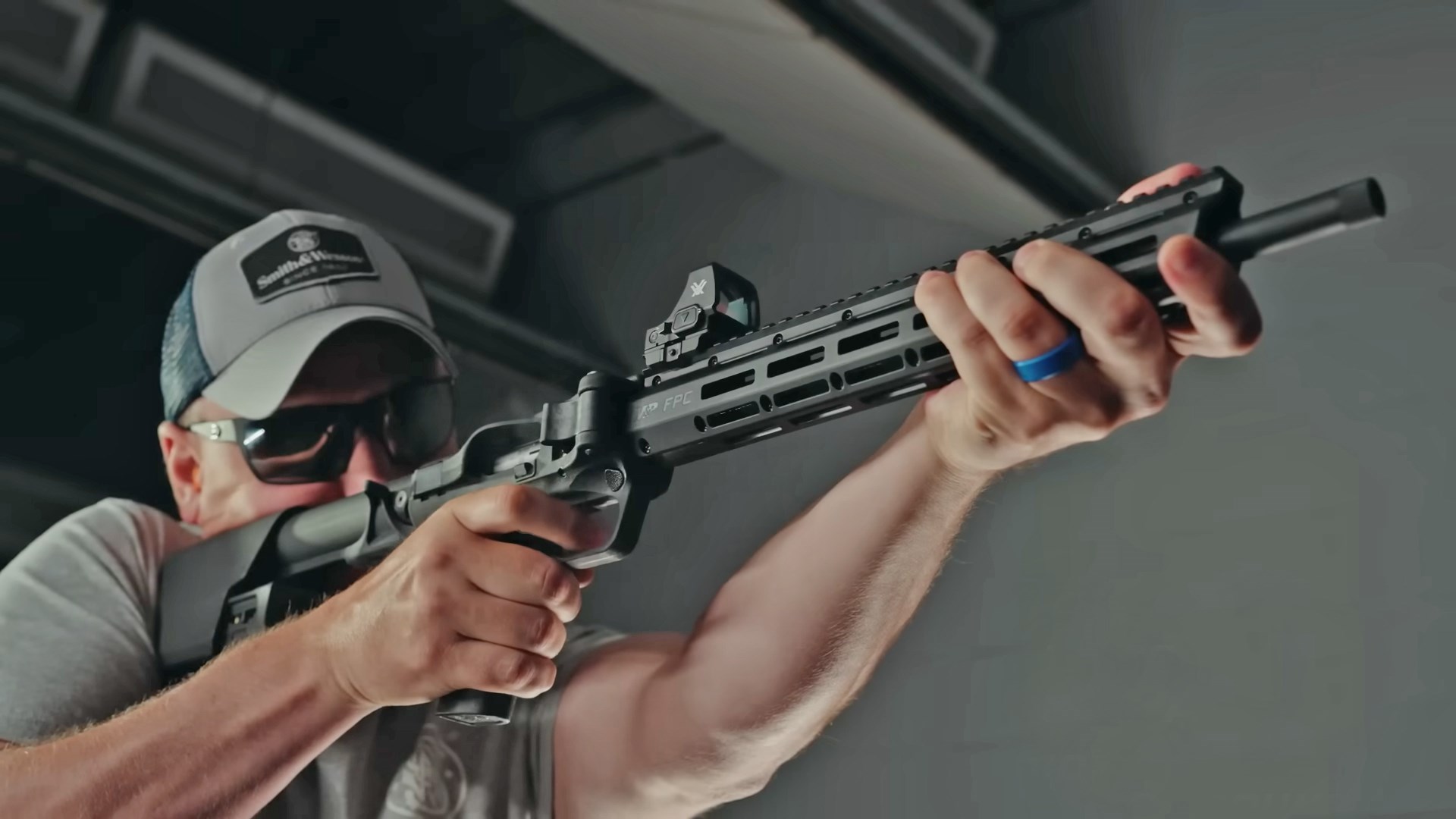 Man aiming the Smith & Wesson FPC 22LR on an indoor shooting range.