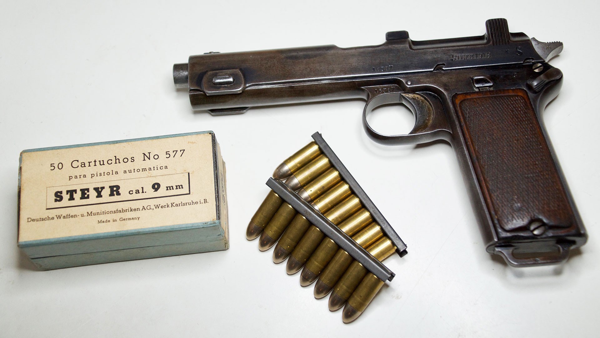 M1912 Steyr pistol on white with ammunition clips box gun left-side view