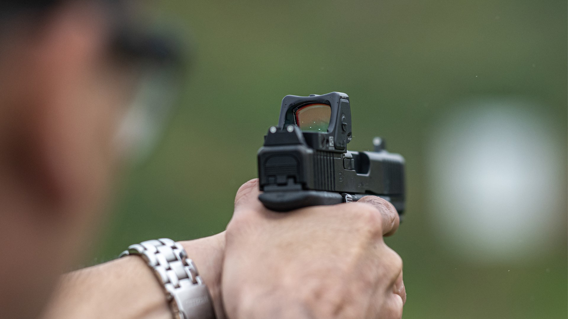 Trijicon RMR HD on glock rear view shooting range hands silver watch blurred background bokeh