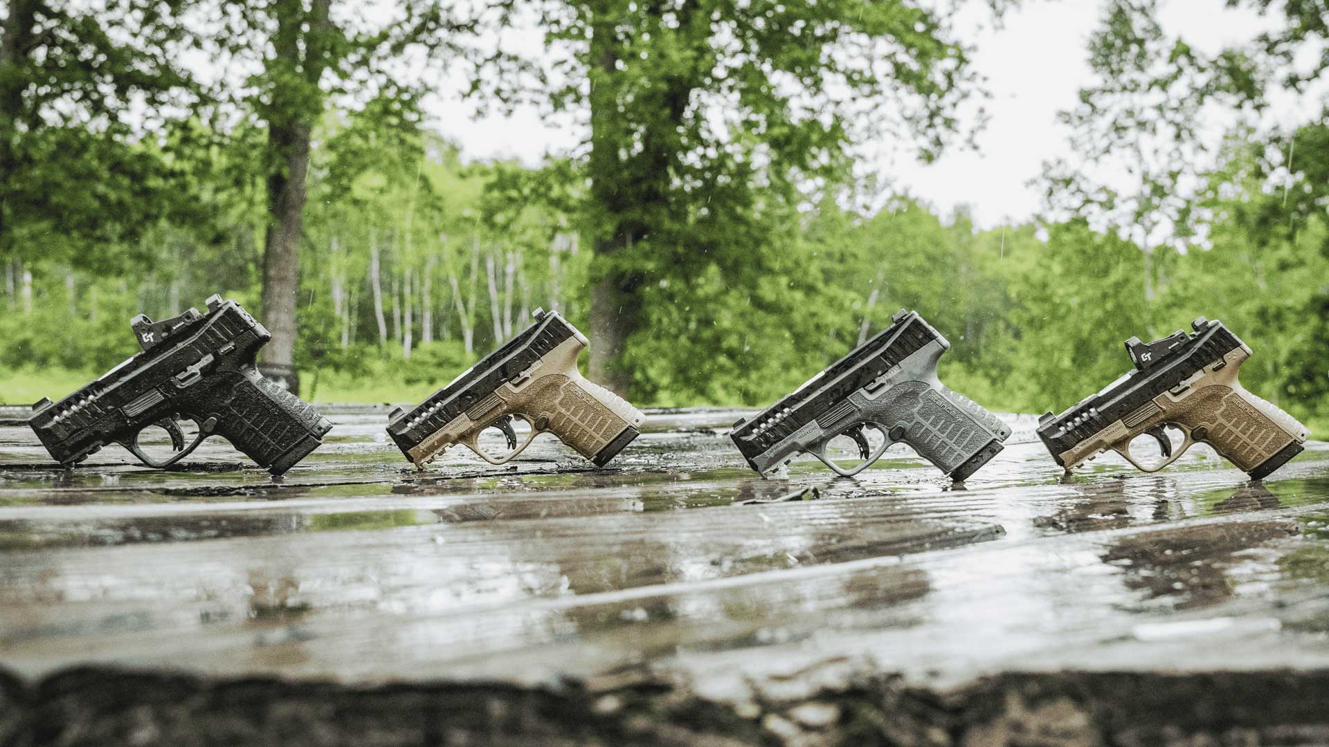 Savage Stance XR pistols lineup row guns outdoors on wet wood four handguns 
