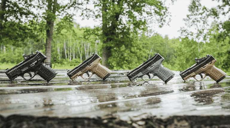 Savage Stance XR pistols lineup row guns outdoors on wet wood four handguns