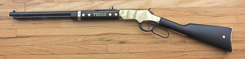 Full length of the left side of the Henry Repeating Arms Texas Tribute Golden Boy lever-action rifle shown on a wood background.