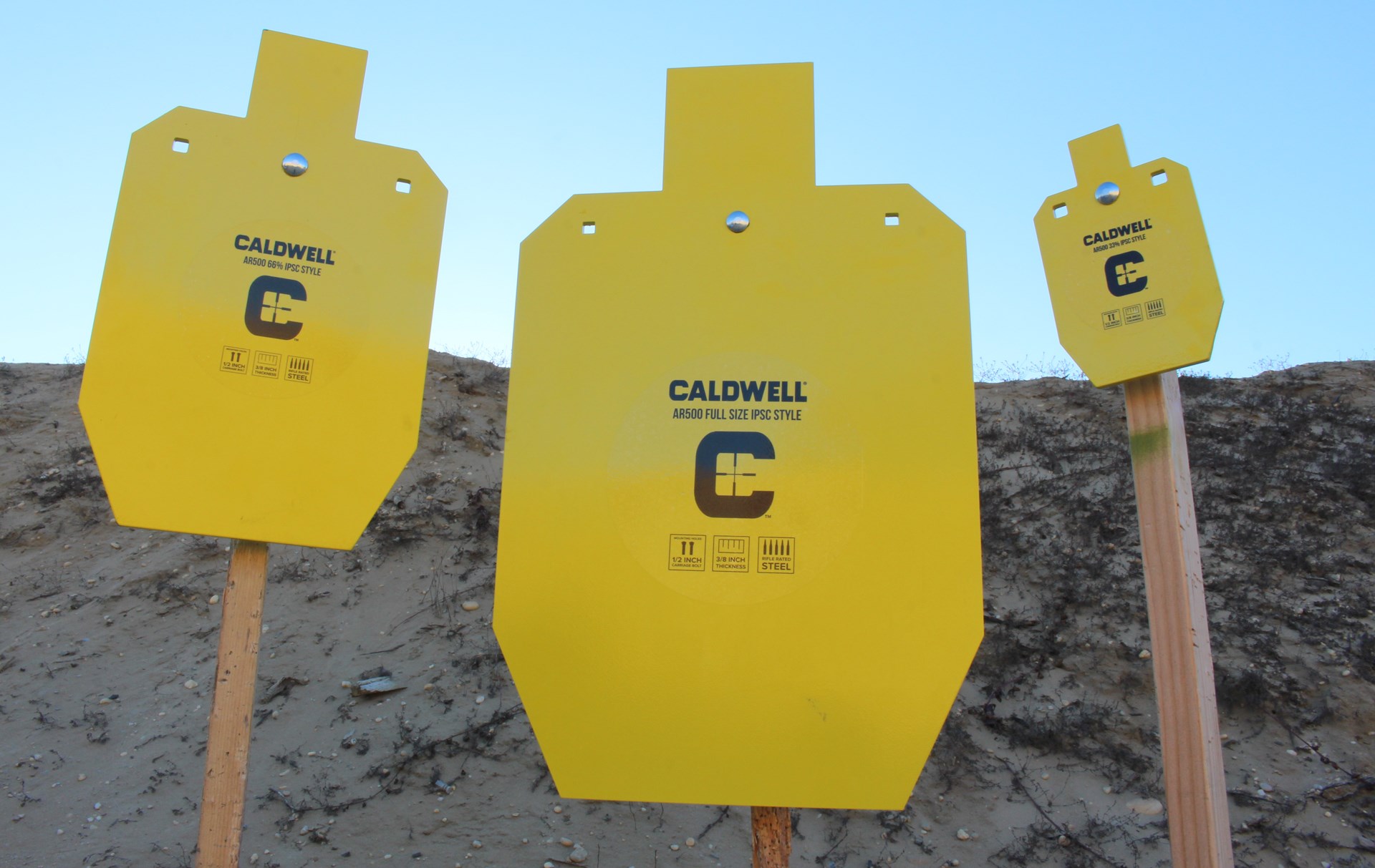 Caldwell steel ipsc targets three orange/yellow metal on post dirt hill background