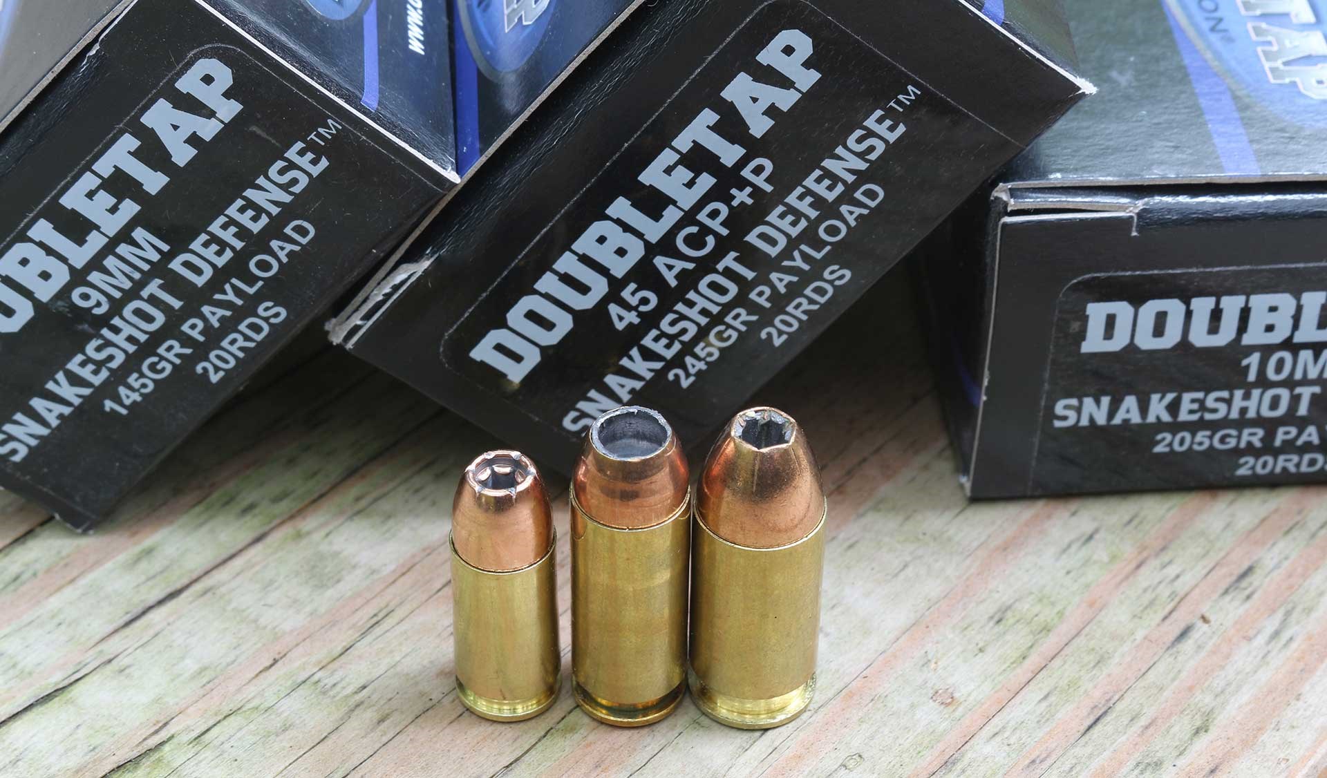 Three different DoubleTap SnakeShot Defense cartridges standing on a wood surface.