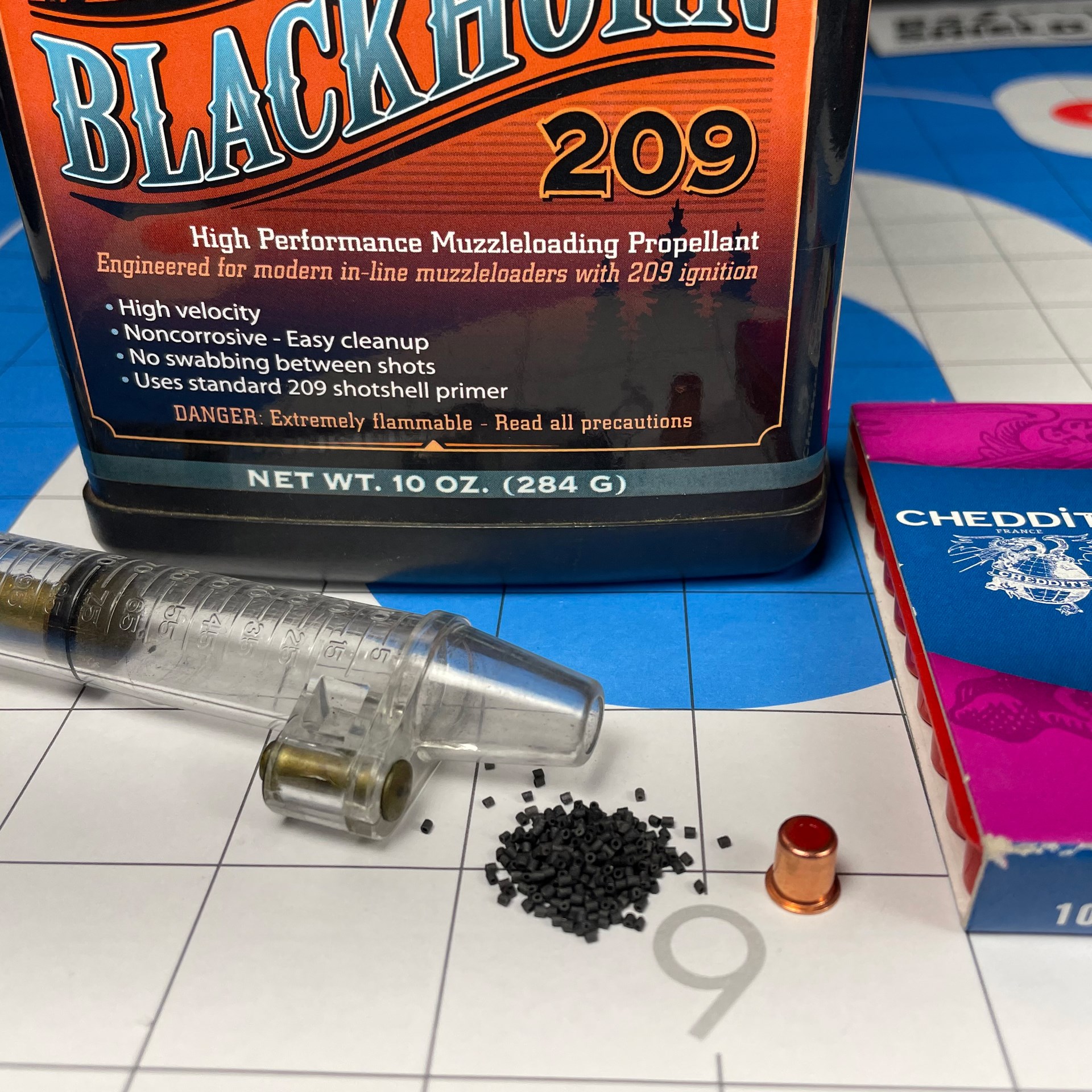 Blackhorn 209 muzzleloading propellant shown with measuring tool and primer