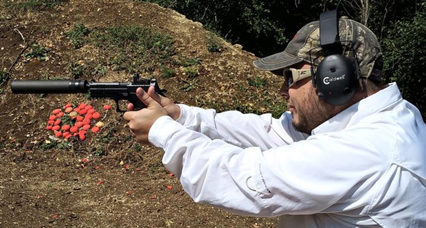 man in white shooting handgun pistol suppressor silencer outdoors