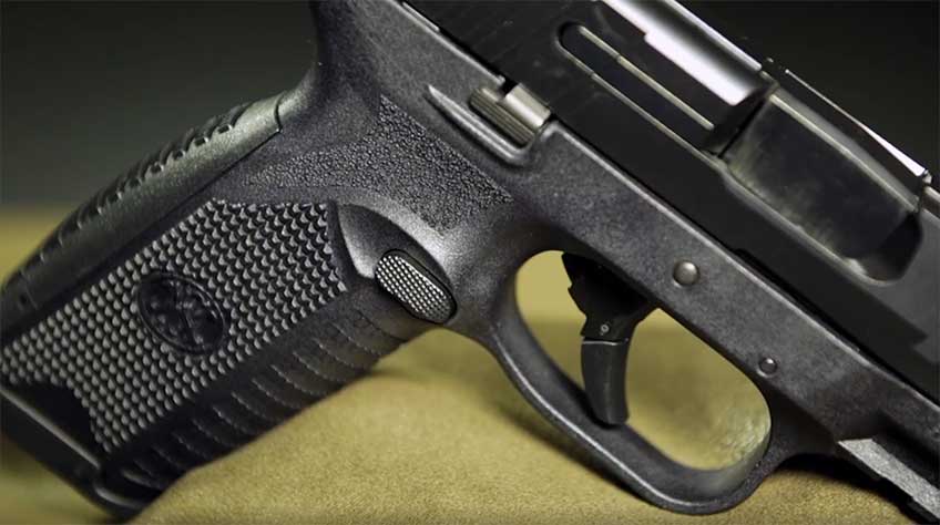 FN 509 right side shown on green background with a closeup of grip texture, trigger and magazine release.