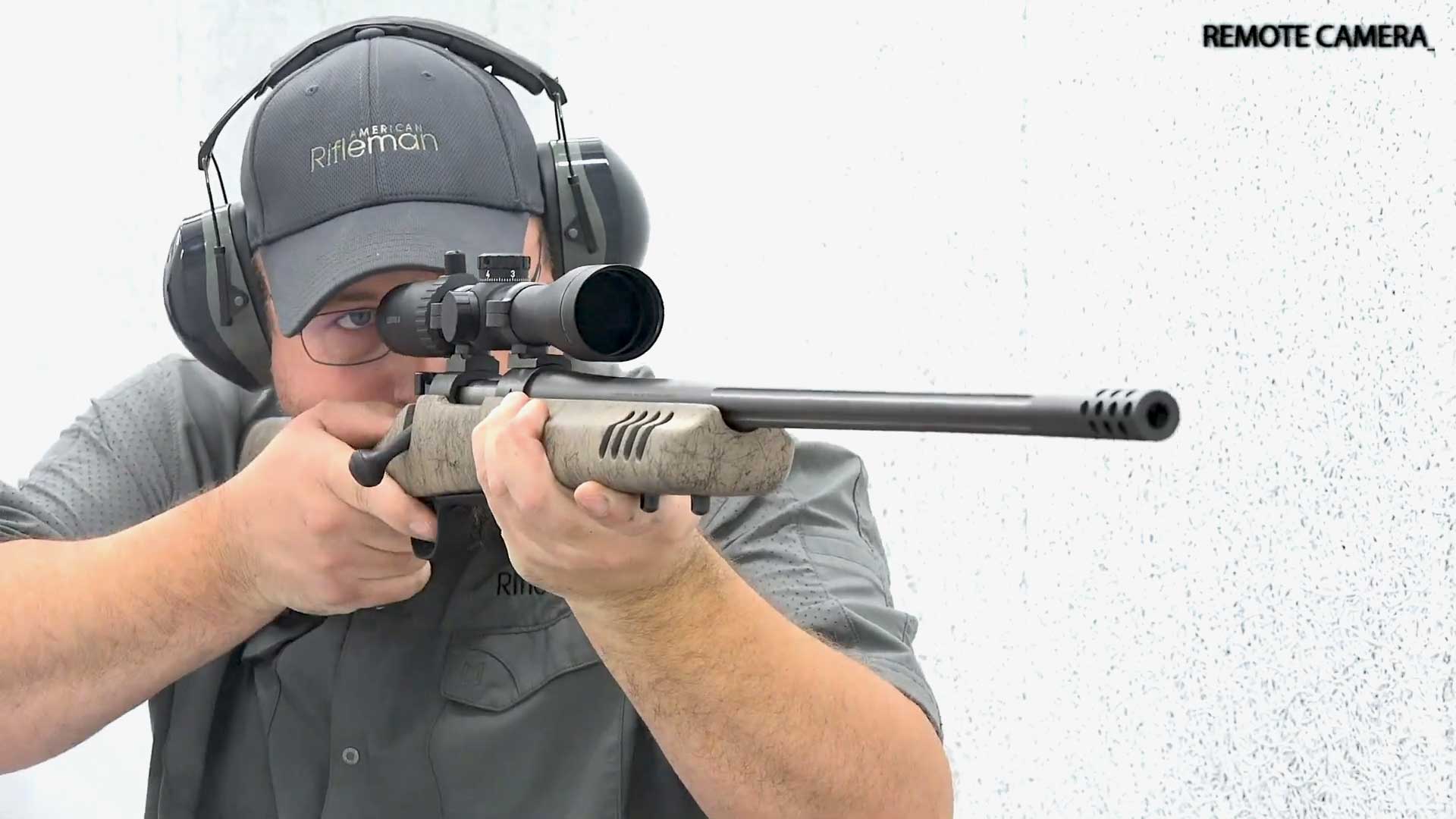 man wearing gray shirt ballcap earmuffs holding standing shooting bolt-action rifle Wincehster Model 70 Long Range MB white shooting range