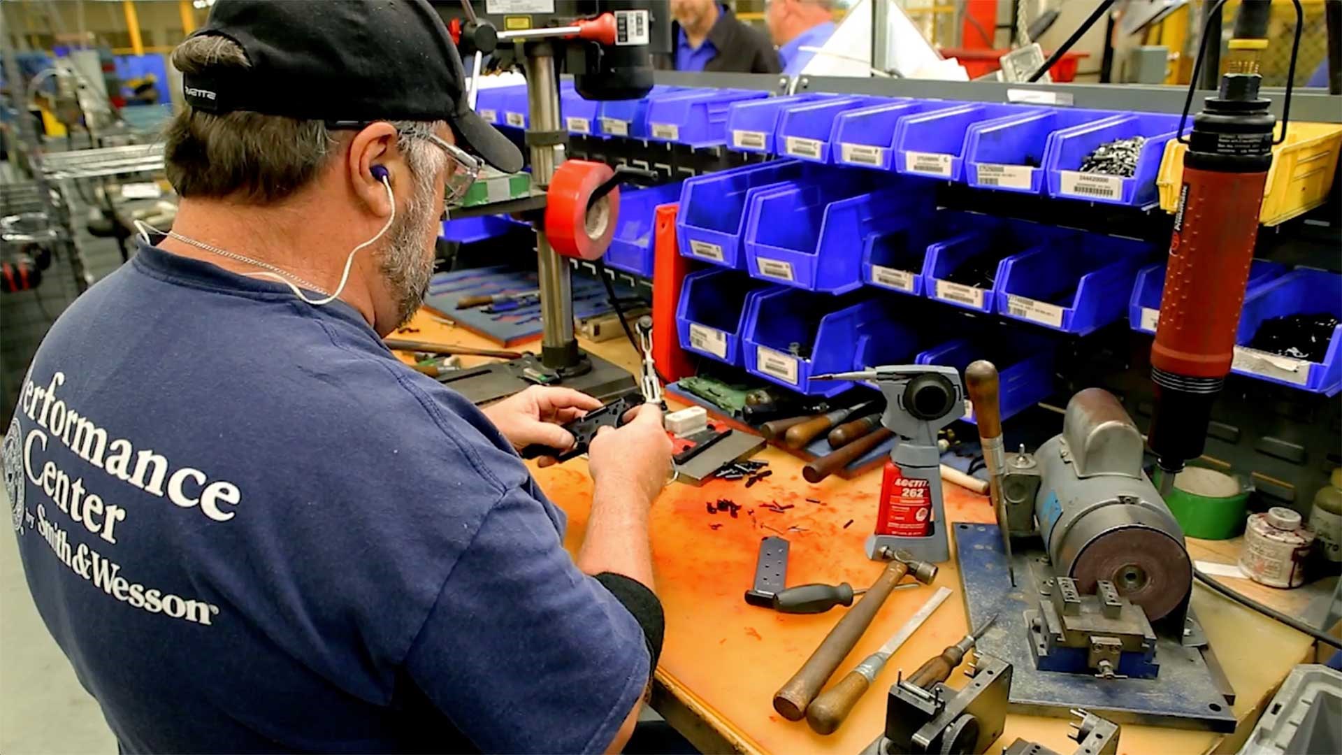 Smith & Wesson Performance Center employee working at a bench assembling a pistol.