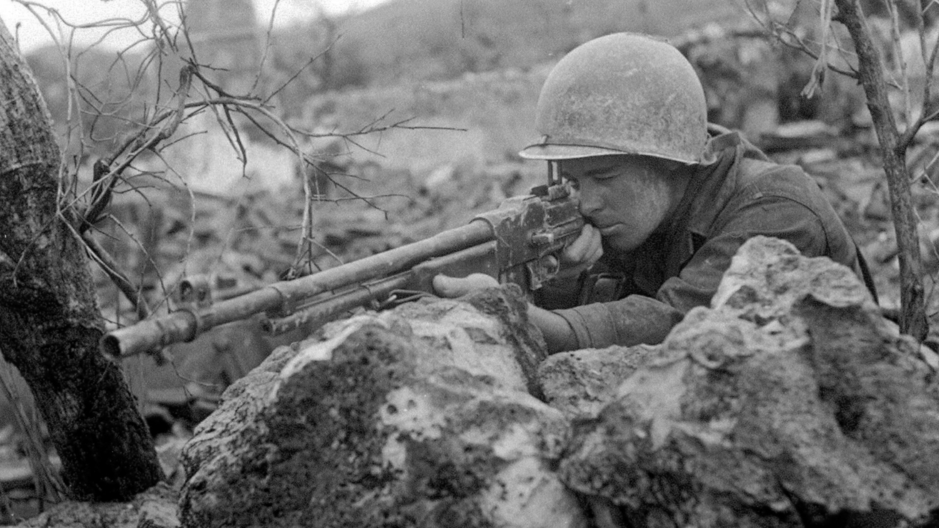 U.S. soldier perched on rocks with BAR