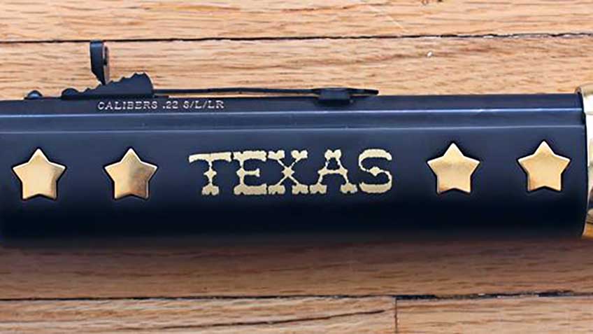 Wooden fore-end of Henry Texas Tribute rifle shown with inlaid five-pointed stars on a dark-stained stock complete with the word &quot;Texas&quot; inlaid in brass.