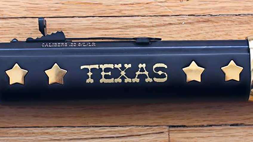 Wooden fore-end of Henry Texas Tribute rifle shown with inlaid five-pointed stars on a dark-stained stock complete with the word &quot;Texas&quot; inlaid in brass.