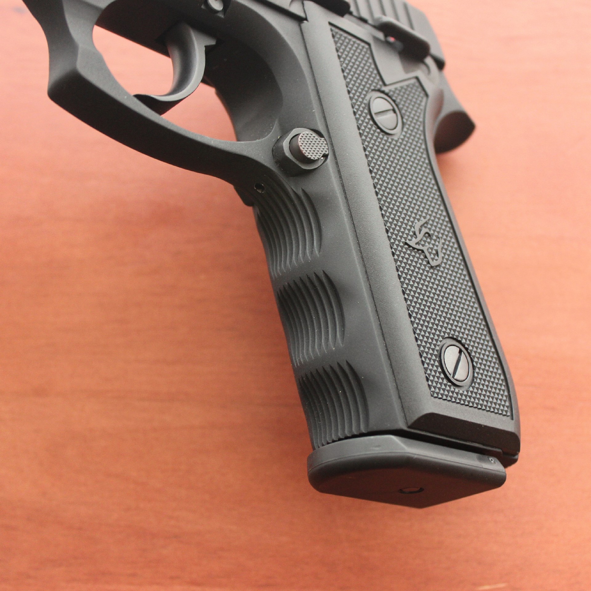 Taurus 917C pistol black color closeup  grip frame controls finger grooves wood table