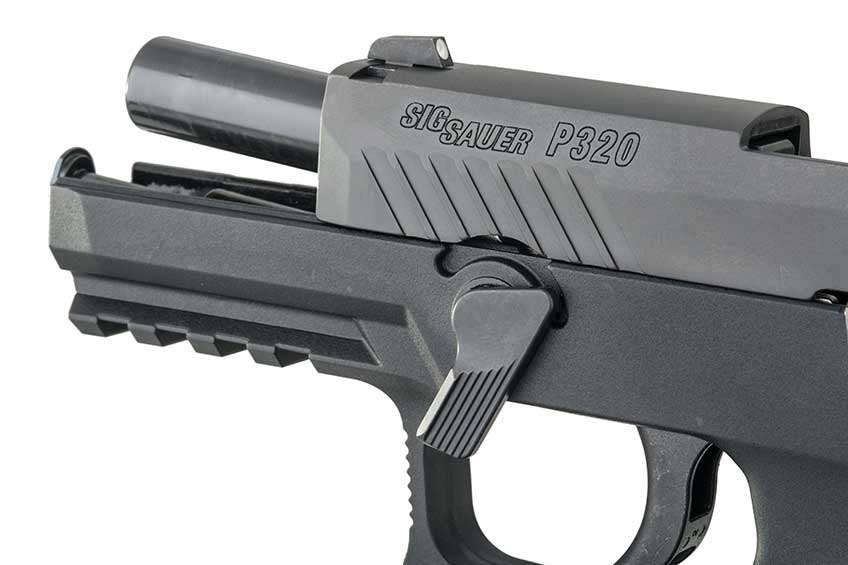 Slide locked back on SIG Sauer P320 with takedown lever rotated into its downward position; on white.