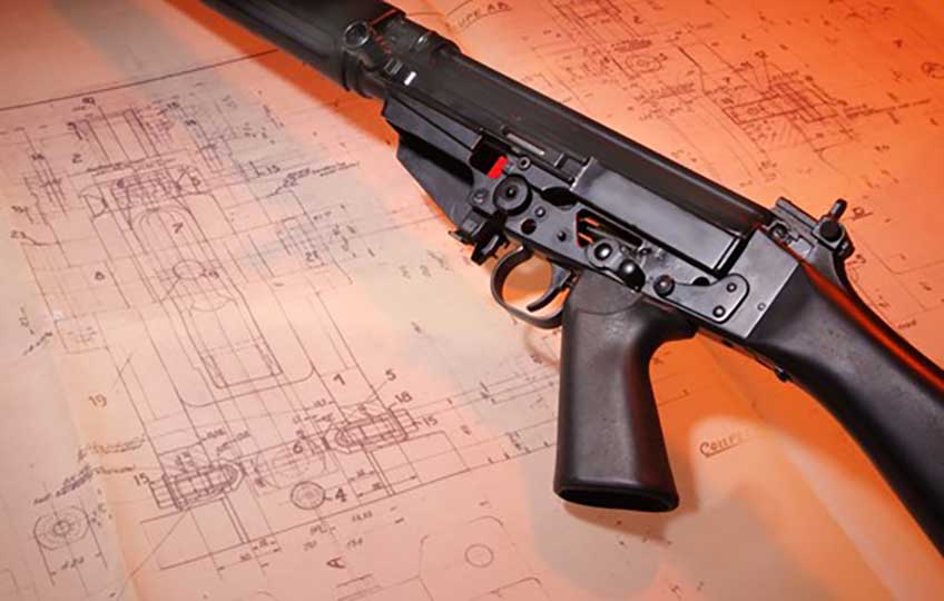 FN FAL with cutaway elements laying on a set of design drawings for the rifle.