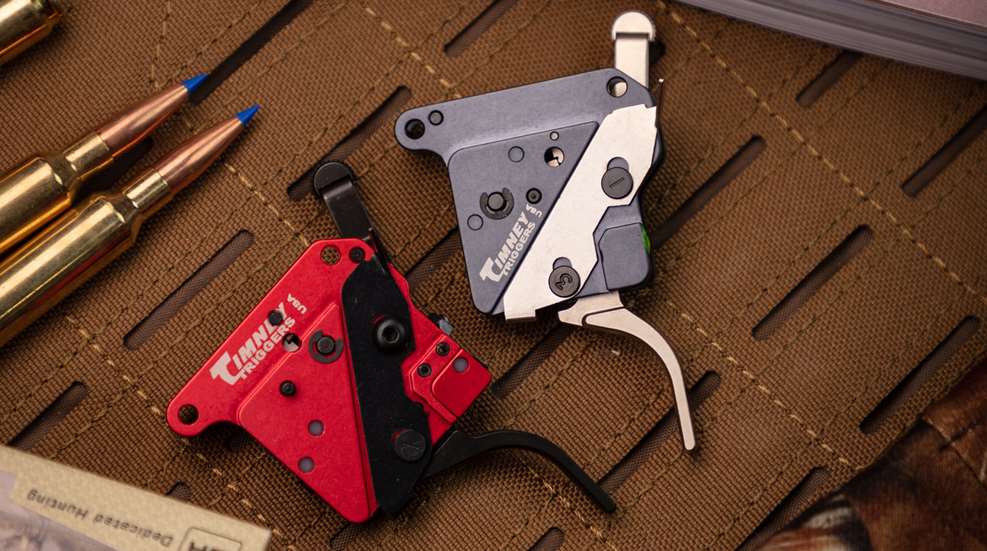 Timney trigger modules on ballistic nylon shown with ammunition cartridges