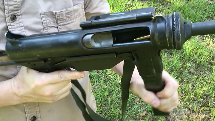 The bolt of the M3A1 cocked to the rear with a magazine inserted. Being an open-bolt submachine gun, you can see the top round of the magazine inside the ejection port.