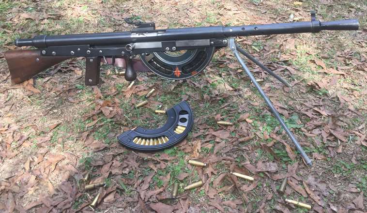 Looking down at a standard version of the French Fusil Mitrailleur Modéle 1915 CSRG Chauchat Light Machine Gun in 8x50 mm R Lebel with ammunition scattered on ground with dirt and leaves.