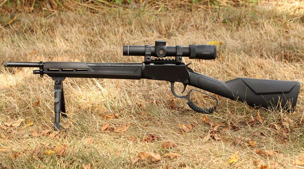 Rossi Rio Bravo Tactical lever-action rifle left-side view shown with bipod in brown grass outdoors with Leupold riflescope attached.