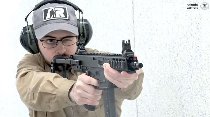 Man on shooting range wearing protective gear and holding a B&amp;T GHM9 pistol.