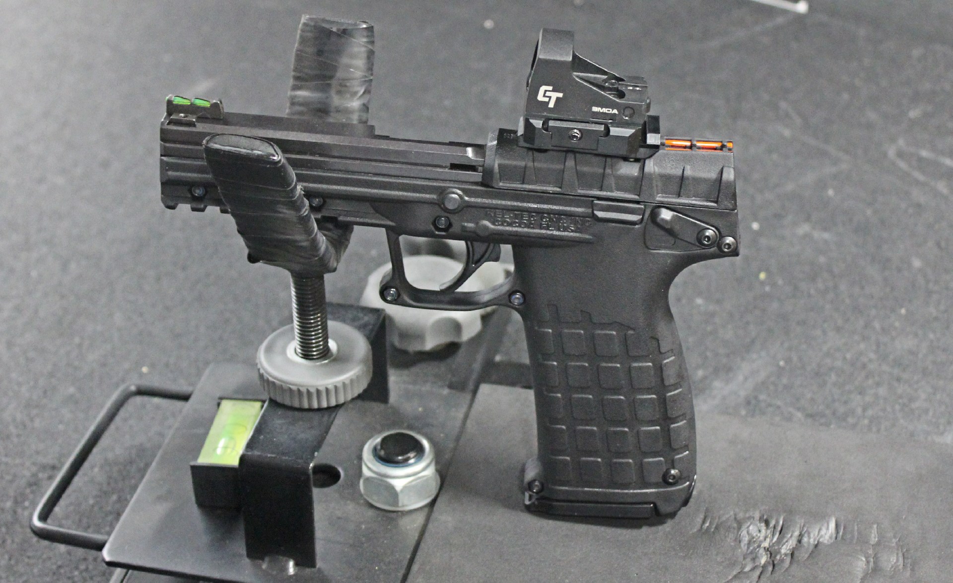 keltec pmr30 .22 wmr pistol with crimson trace red-dot optic shown resting in cradle on shooting bench indoors black matting