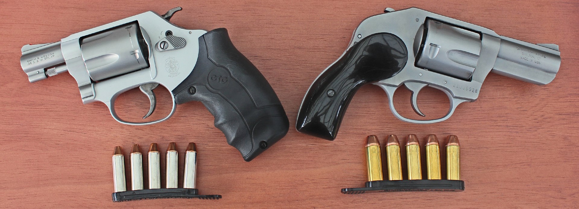 smith and wesson j-frame left compared to right charter arms bulldog guns revolvers with ammunition on wood table