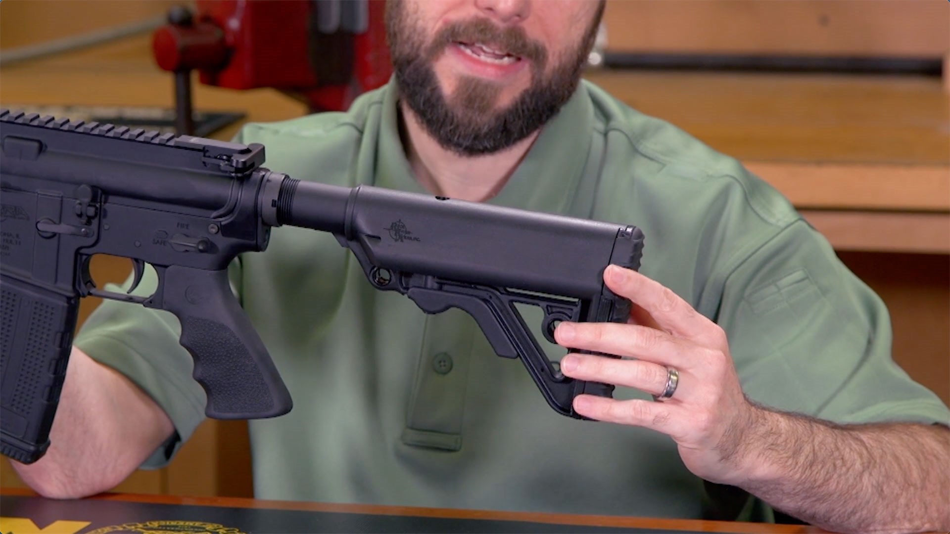 Man in a green shirt showing the black buttstock on the Rock River Arms Assurance Carbine.